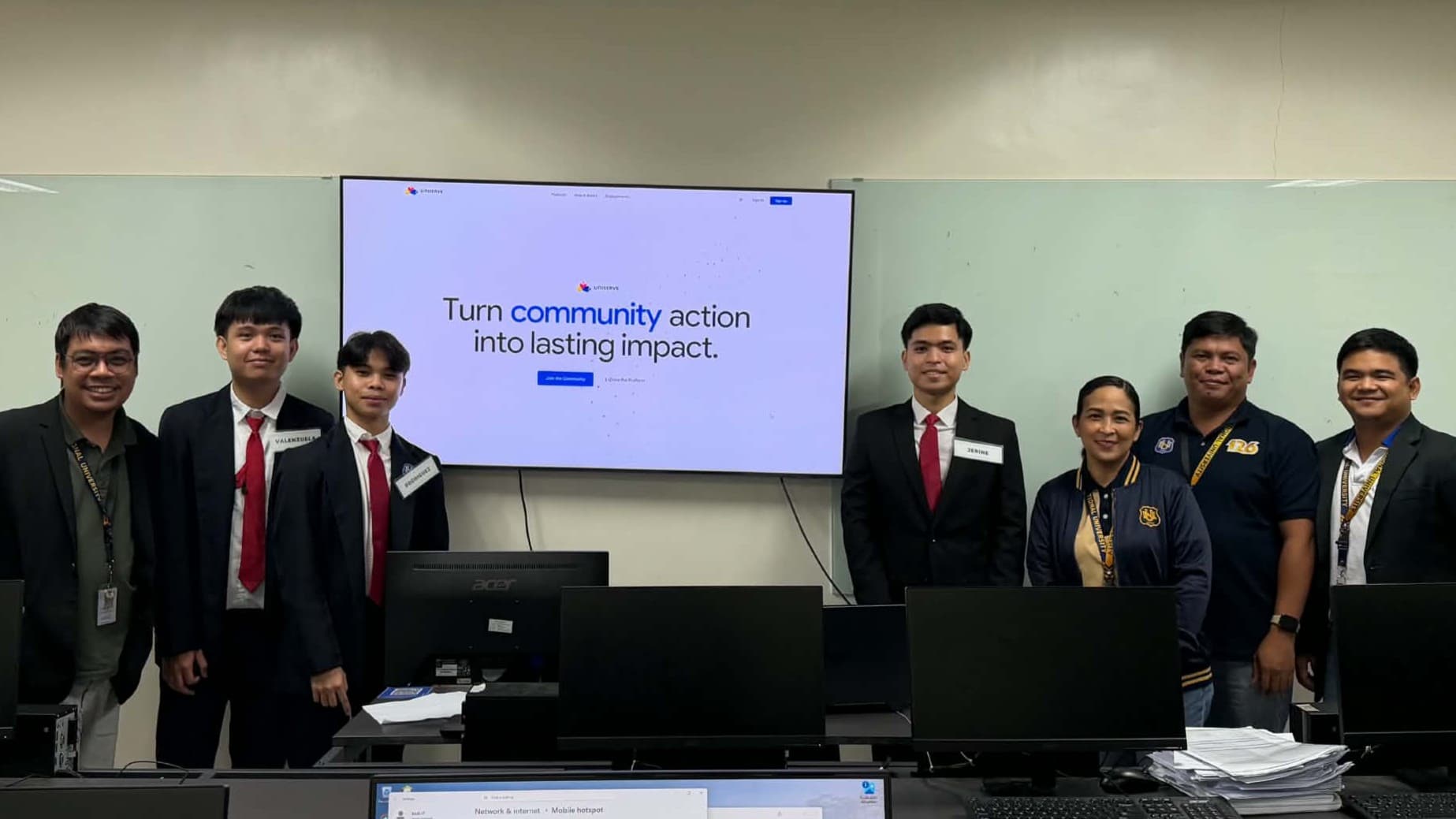 UNISERVE capstone team at the Capstone 2 defense, with the application displayed in the background.